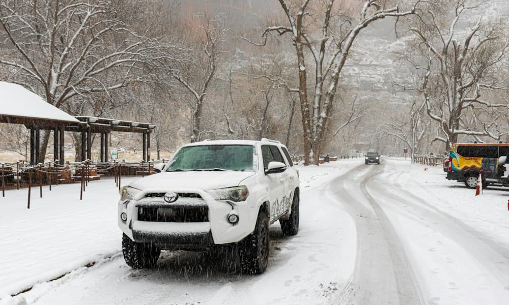 White 4x4 SUV on a snowy mountain road during snowfall