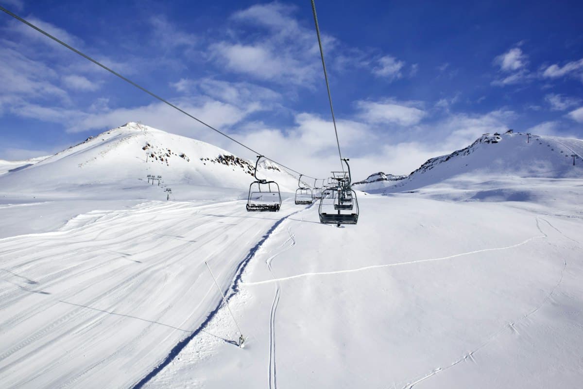 Chairlift climbing a snowy slope under a clear blue sky